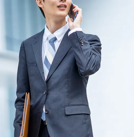 屋外で電話応対するスーツを着た男性