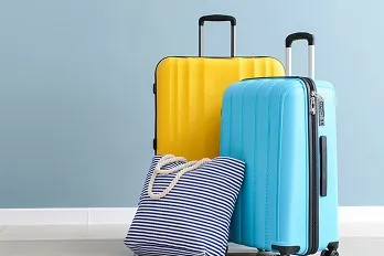 青空のような水色の壁を背にした、旅行カバンの並び。